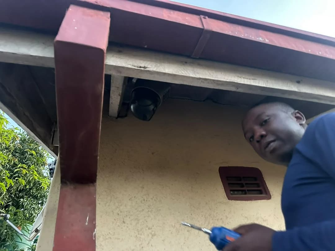 Wikilax Tech Solutions technician working beneath an installed exterior Wi-Fi camera